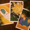 Photo of three advent cards, each showing a color illustration. One is of baby Jesus in the manger, one of the angels in the sky over the shepherds, and one of four advent candles.