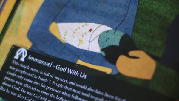 Closeup photo of the Gospel Story Hymnal, showing an illustration of baby Jesus, and a note titled "Immanuel - God With Us."
