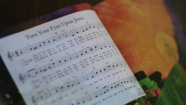 Photo of a page from the Gospel Story Hymnal, showing the hymn "Turn Your Eyes Upon Jesus" on one side, and a bright illustration on the other.